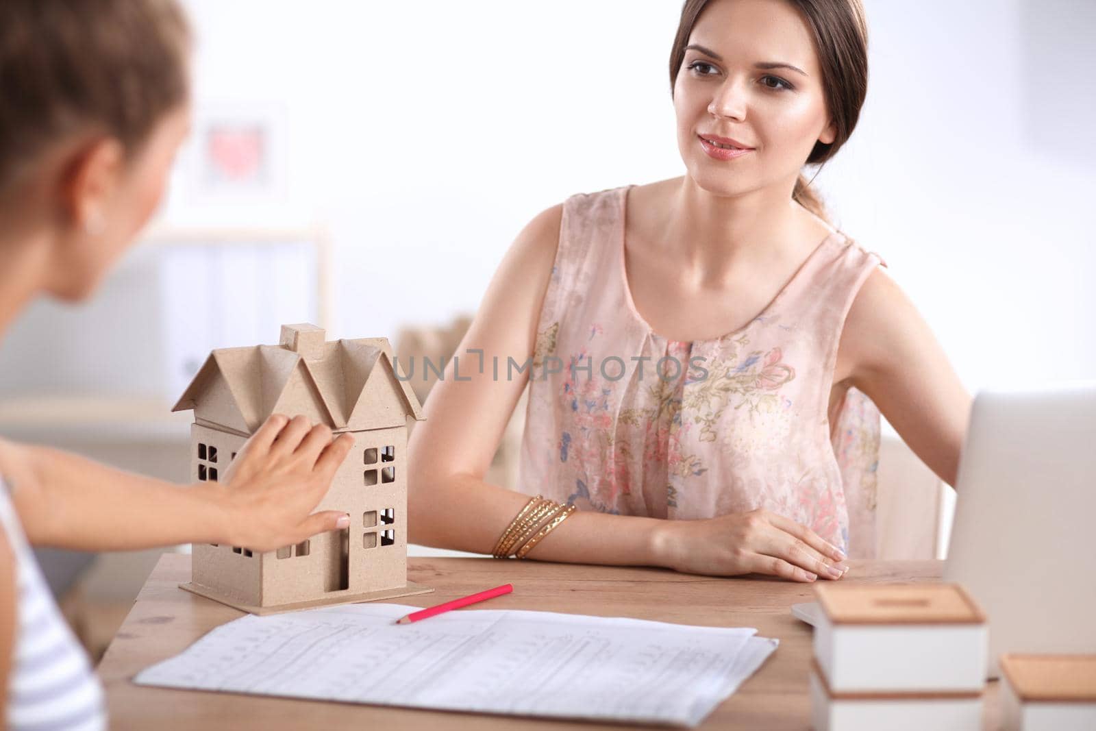 Attractive businesswoman sitting on desk in the office by lenetstan