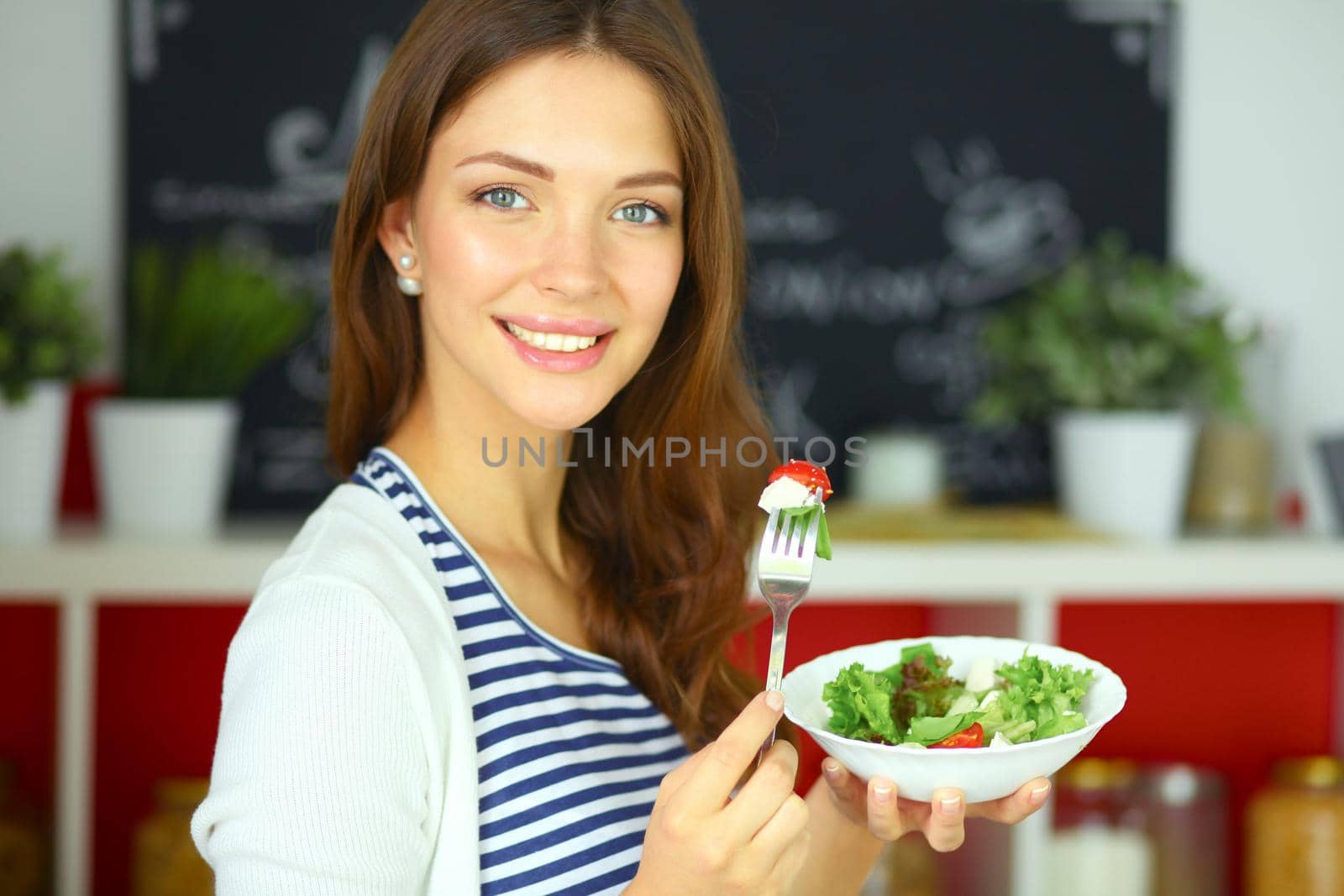 Young woman eating salad and holding a mixed by lenetstan