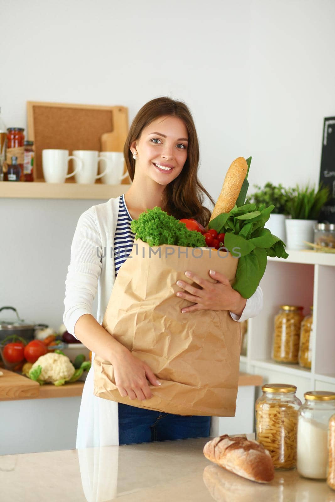 Young woman holding grocery shopping bag with vegetables .