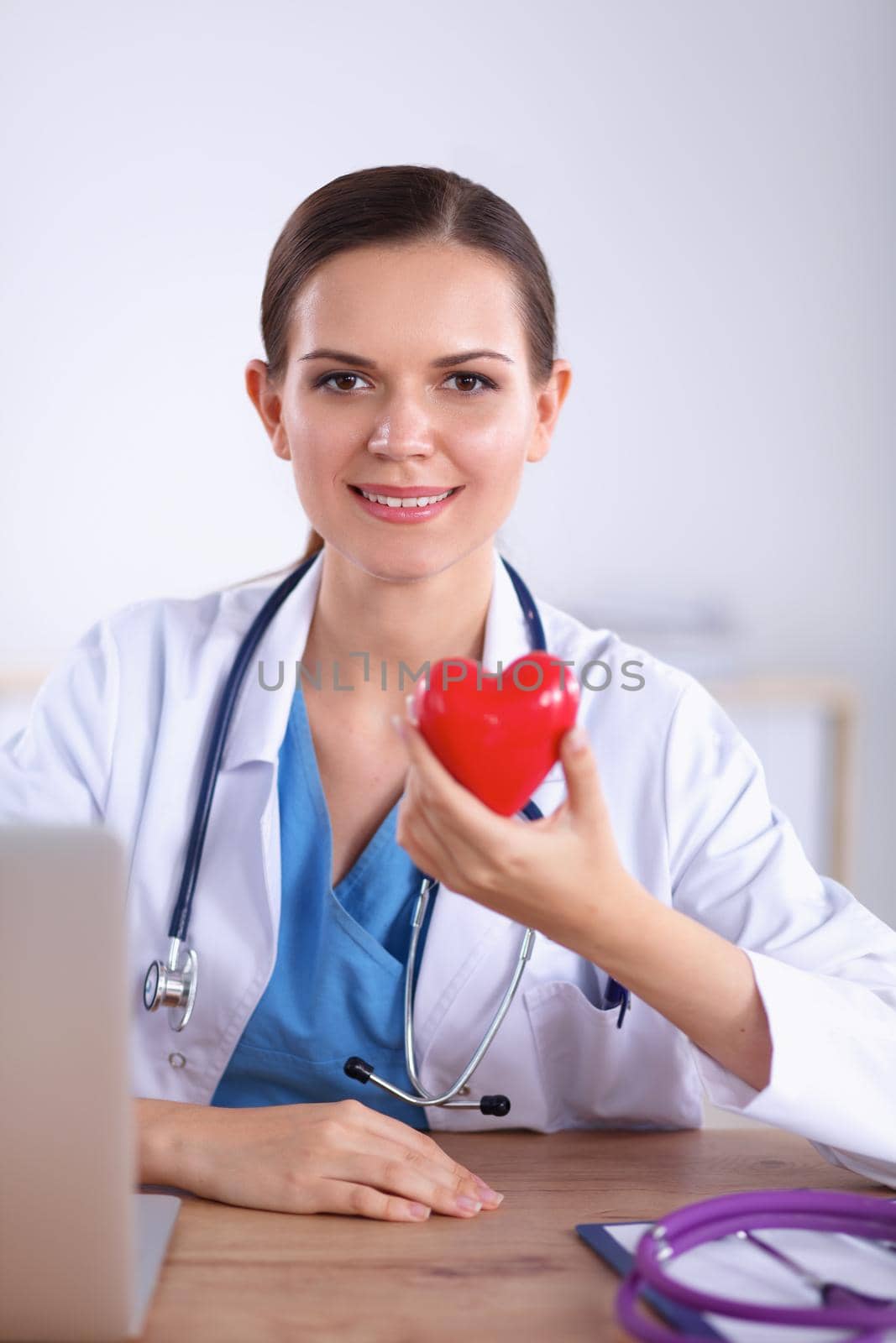 Happy doctor with red heart symbol at desk