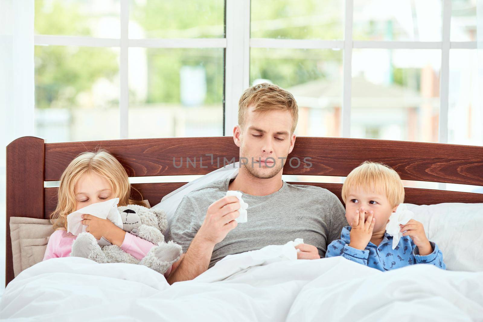 Sick family of three having runny noses lying in bed together at home. Virus disease. Coronavirus concept. Sick family at home. Healthcare concept