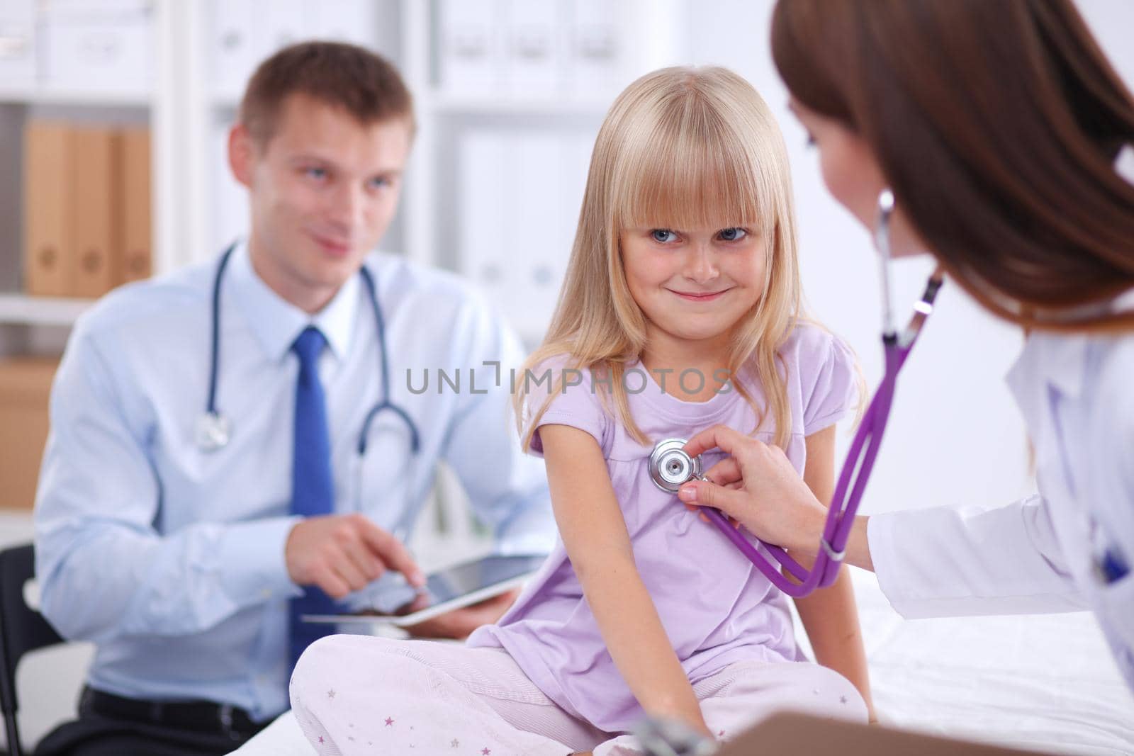 Female doctor examining child with stethoscope at surgery.