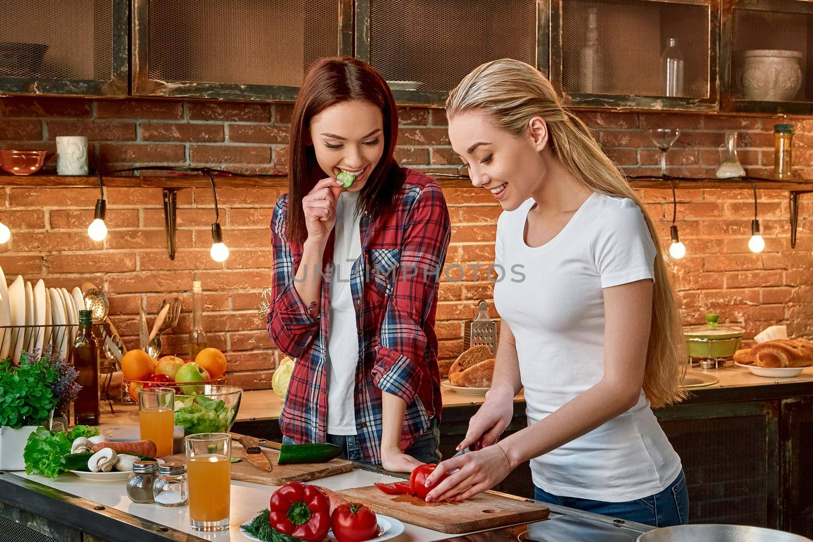 Salad Always and Forever. Smiling young women cutting vegetables in modern kitchen. Cozy interior. by friendsstock