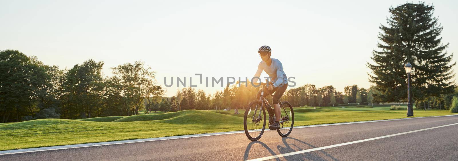 Website header of Rear view of athletic man in sportswear standing with bicycle on the road. Riding mountain road bike on a sunny summer day by friendsstock