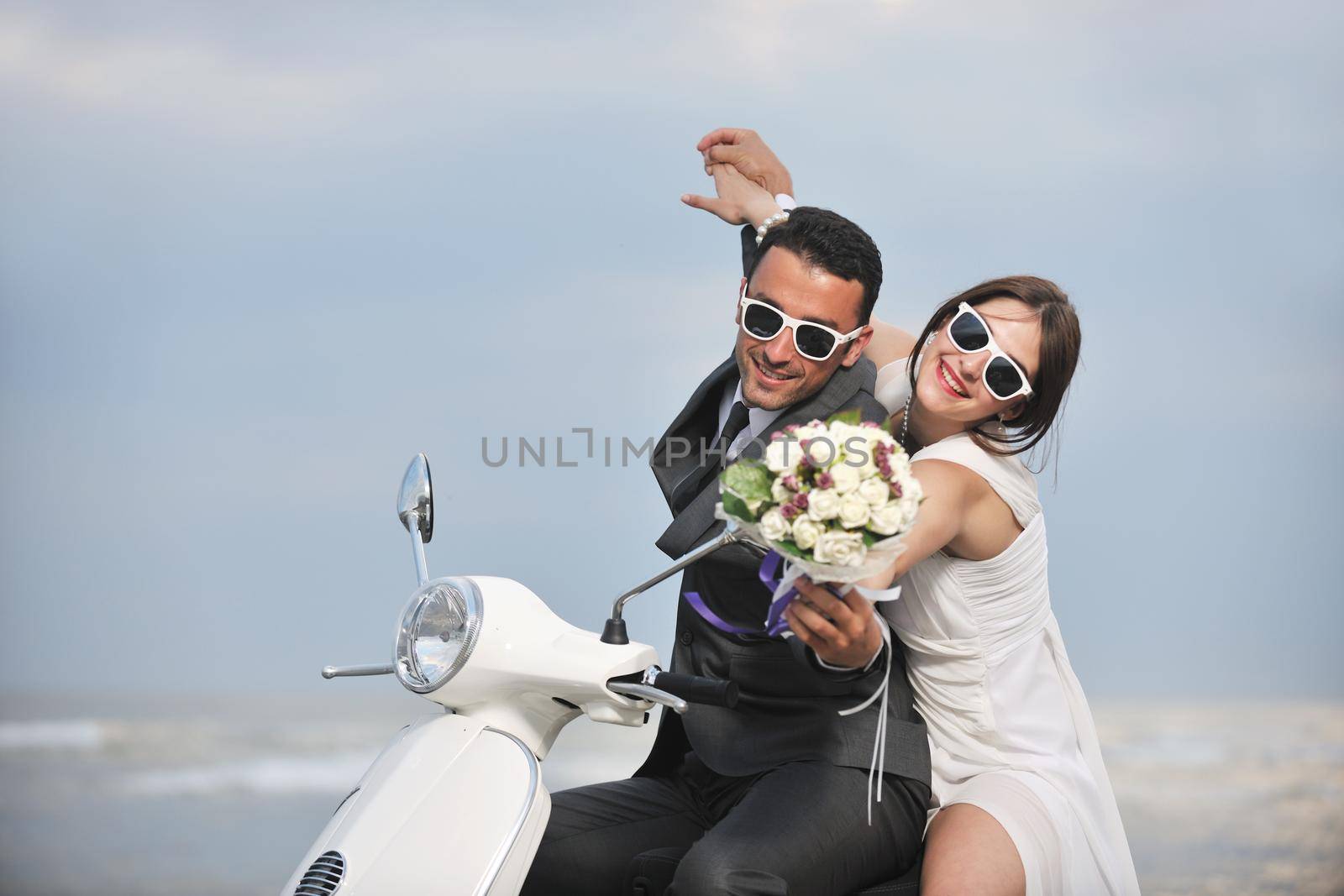 just married couple on the beach ride white scooter by dotshock