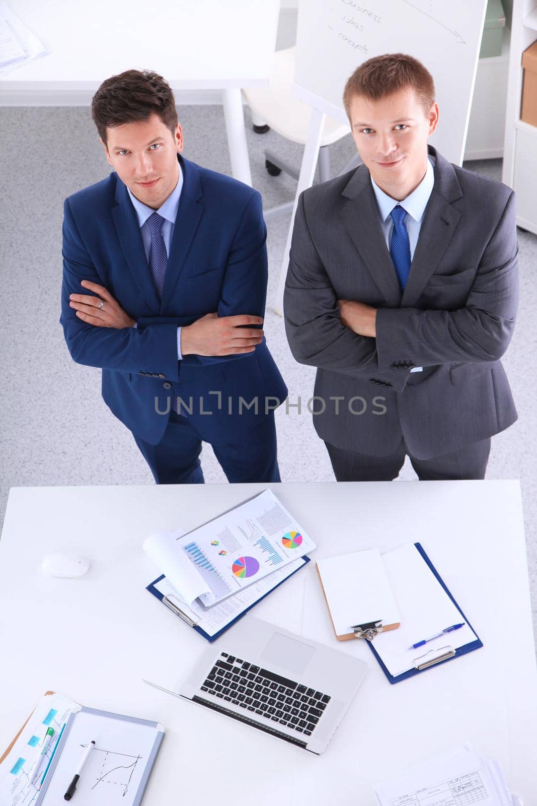 Two businessmen standing with a blank sheet of paper by lenetstan