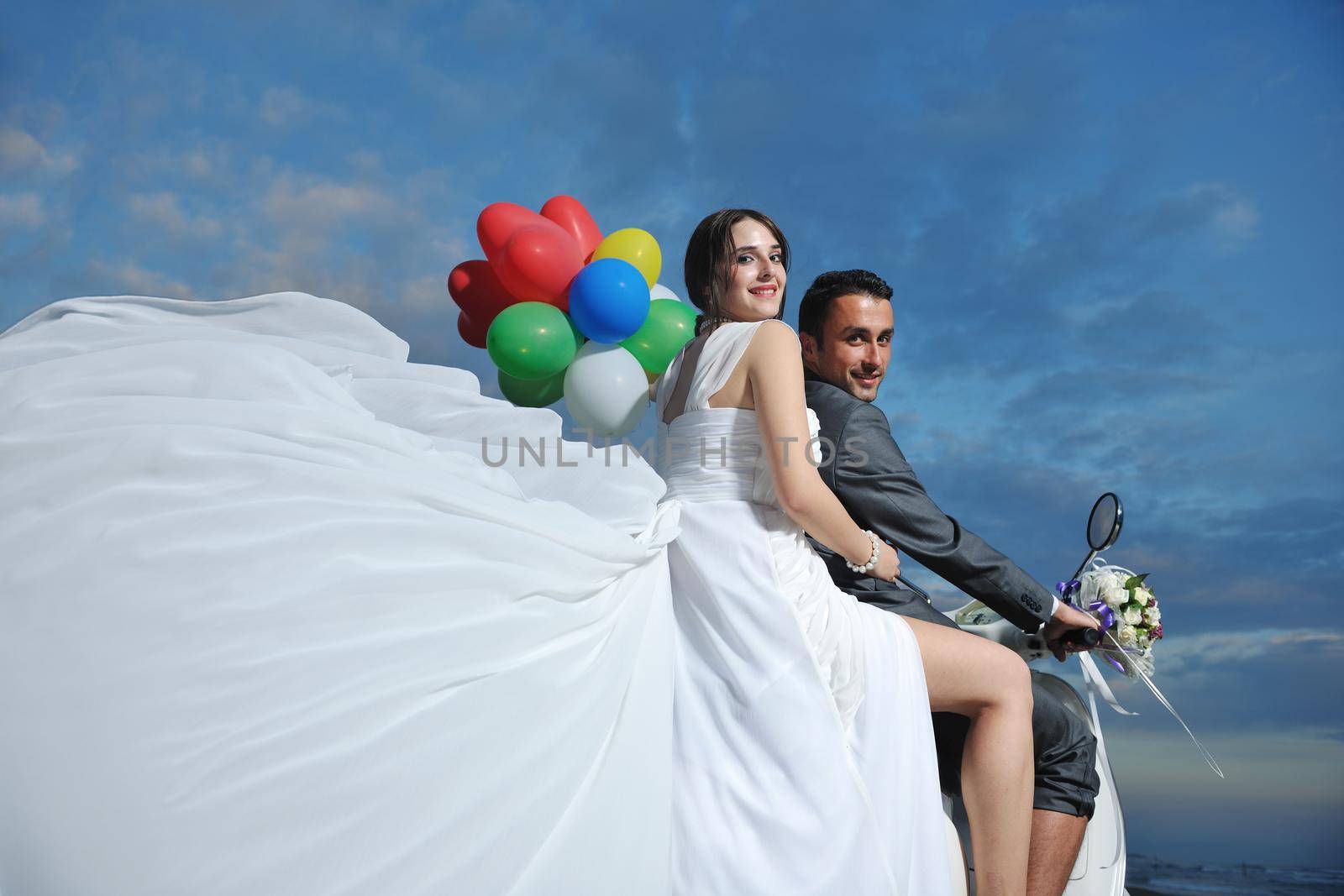 just married couple on the beach ride white scooter by dotshock