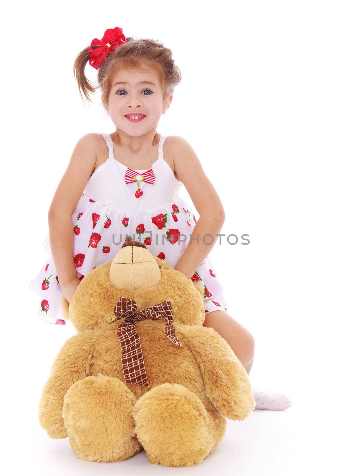 Cute little girl in a light summer dress that hugs a Teddy bear - Isolated on white background