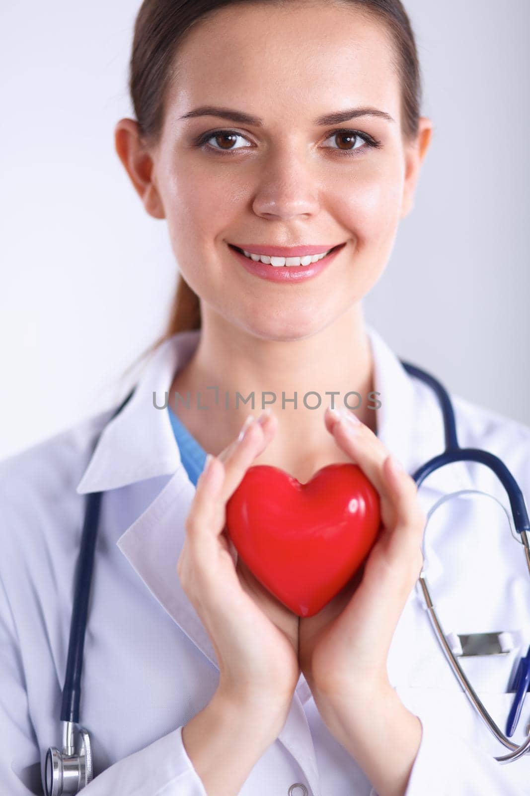 Young woman doctor holding a red heart, isolated on white background by lenetstan