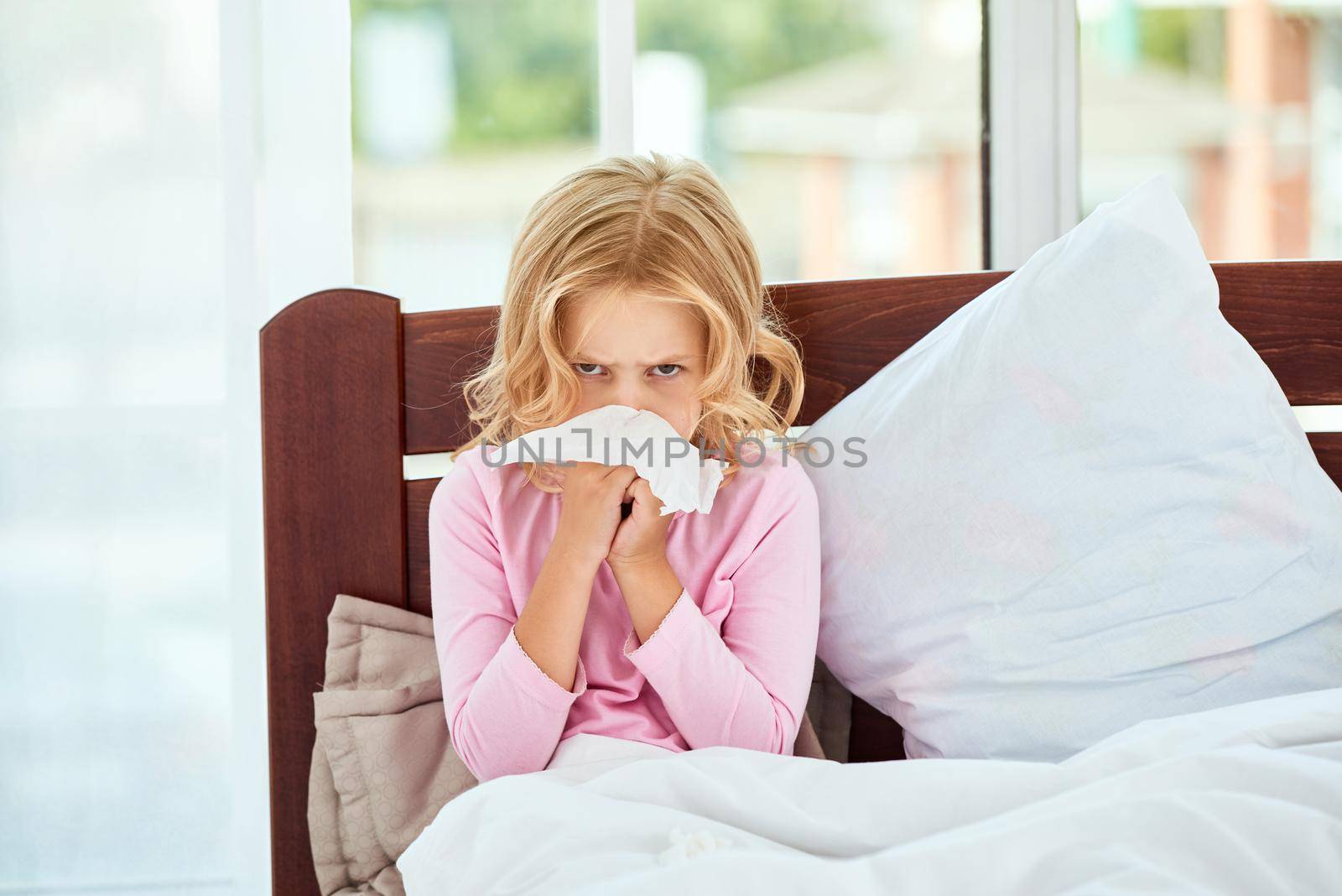 Little girl with runny nose suffering from cold or flu while lying in bed at home. Virus disease. Coronavirus concept. Healthcare concept