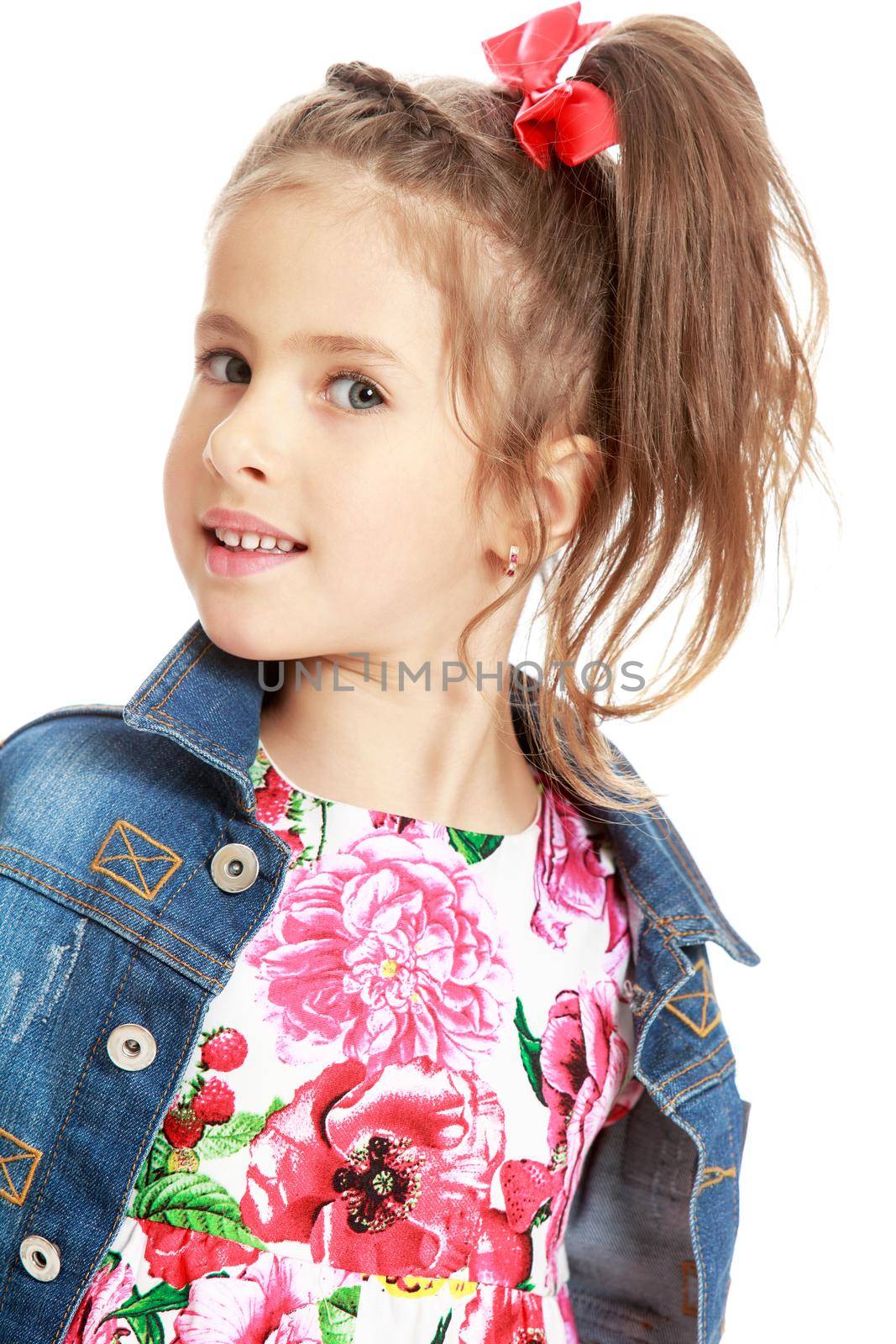 Cute little girl in dress ,denim jacket and red bow on her head . The girl is looking directly into the camera . close-up - Isolated on white background