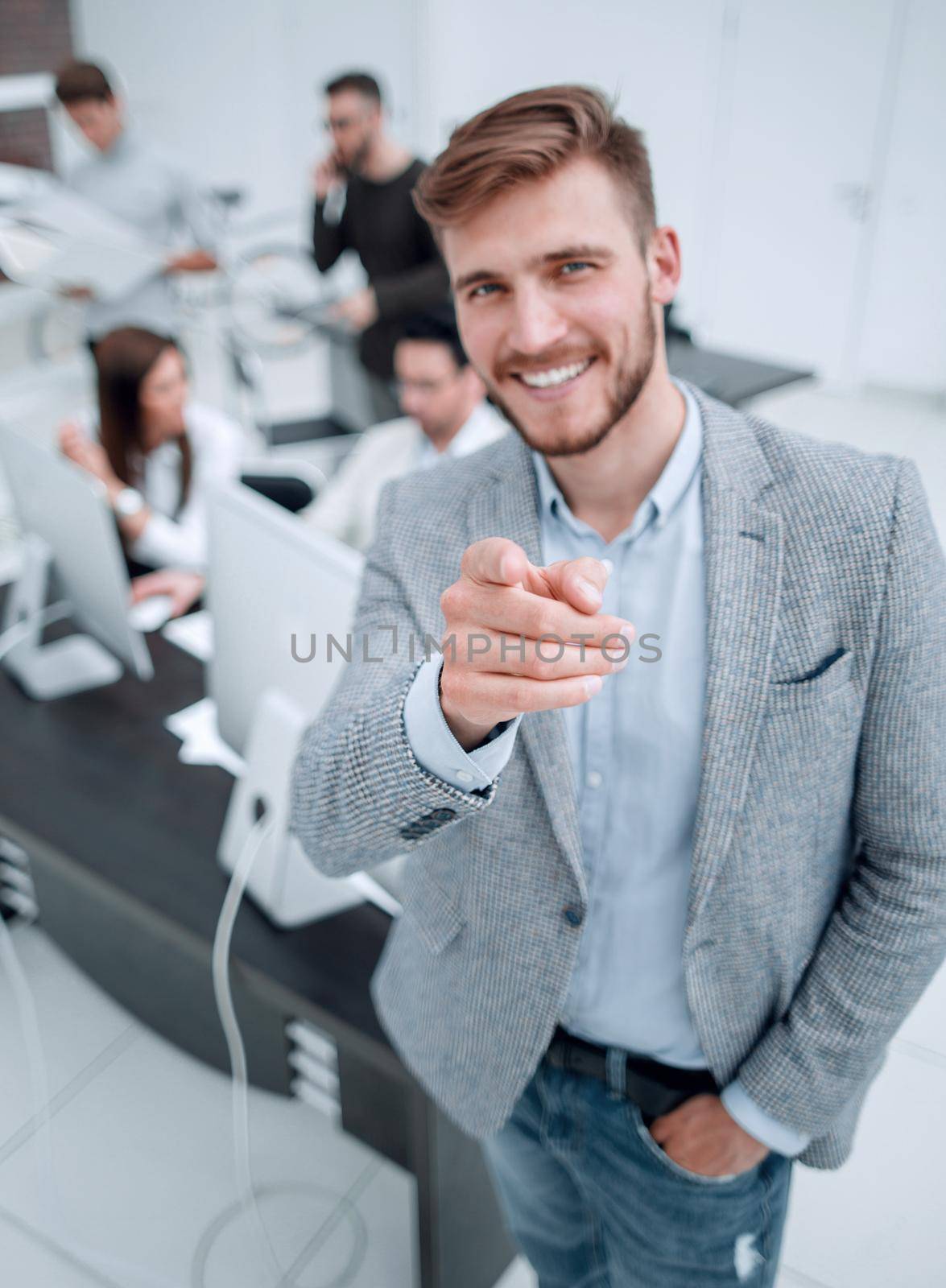 young businessman standing in the office and pointing at you by asdf