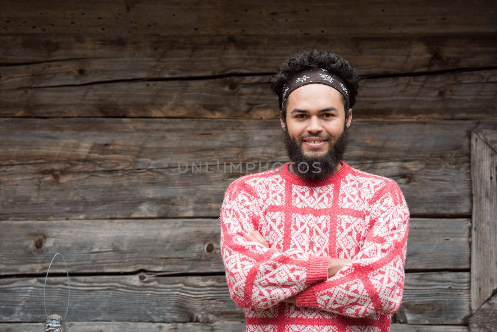 portrait of young hipster,  man with beard in front of old vintage wooden house