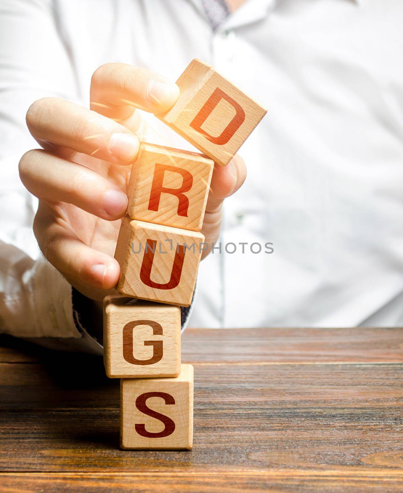 Man breaks tower blocks with word Drugs. Combating the illicit manufacture and distribution of dangerous drug chemicals. Prevention, information campaign. Addiction rehabilitation. Stop doing drugs