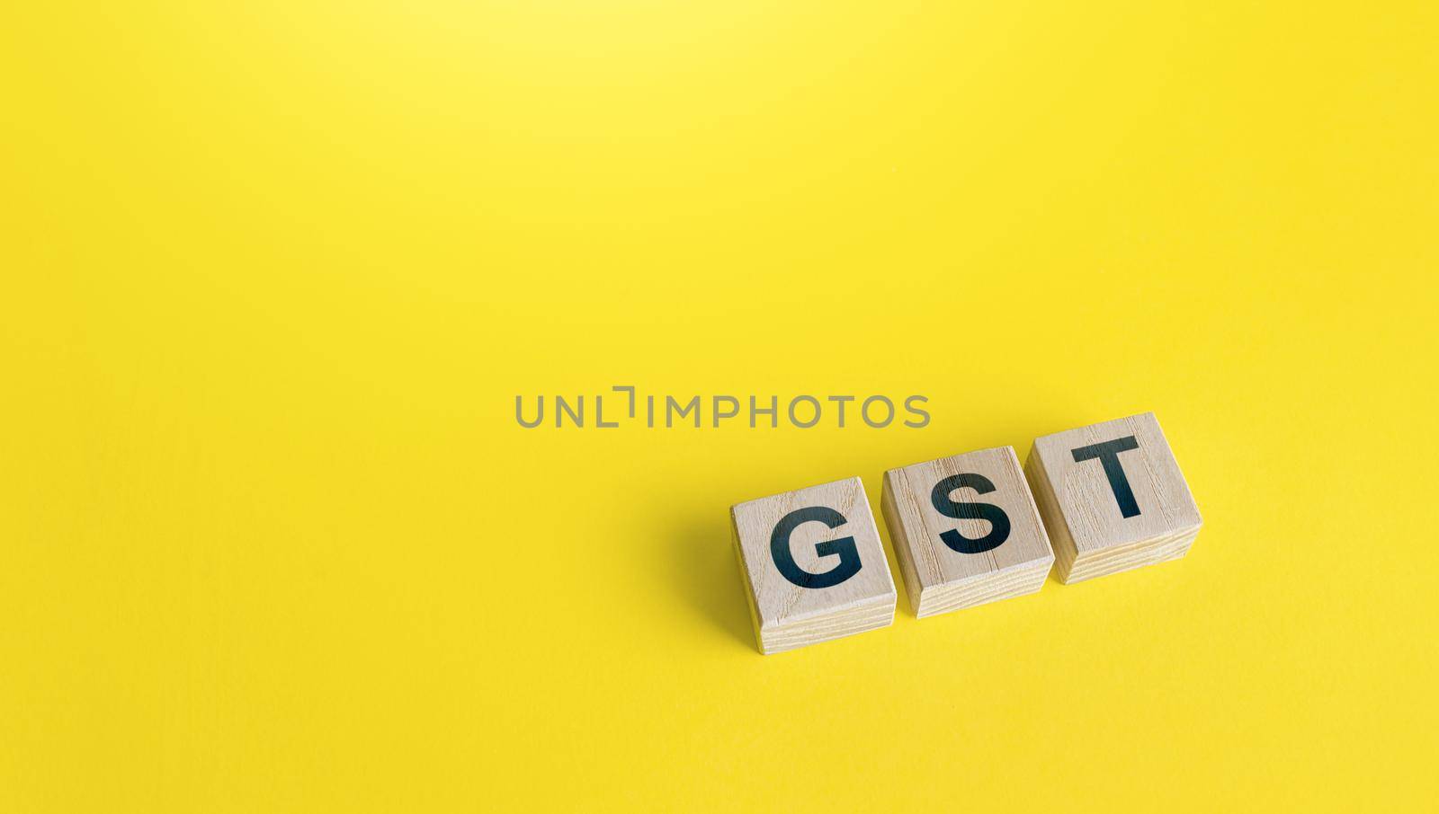 Blocks with letters GST (Goods and Services Tax) on a yellow background. State financial policy to regulate tax collection rules and reduce bureaucratic burden. Investments, ease of doing business. by iLixe48