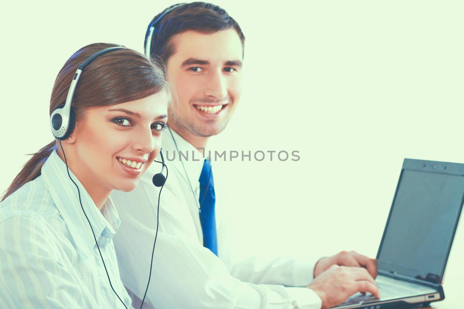 Young business woman and handsome businessman in headsets using laptops while working in office.