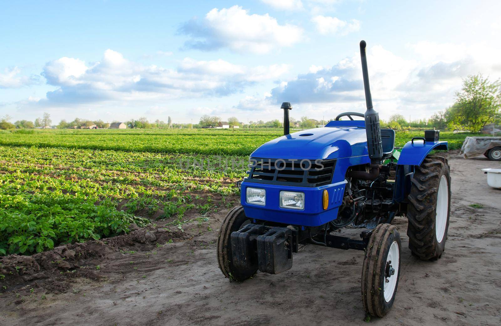 Blue tractor without driver near a farm field. Agricultural machinery and technology. Organization of agricultural activities, business planning. Support for farmers with subsidies and loans. by iLixe48