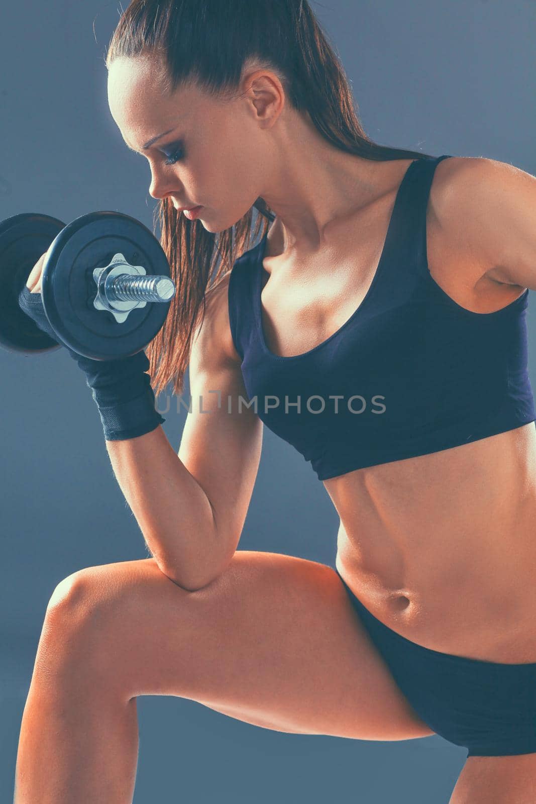 Athletic woman pumping up muscules with dumbbells.
