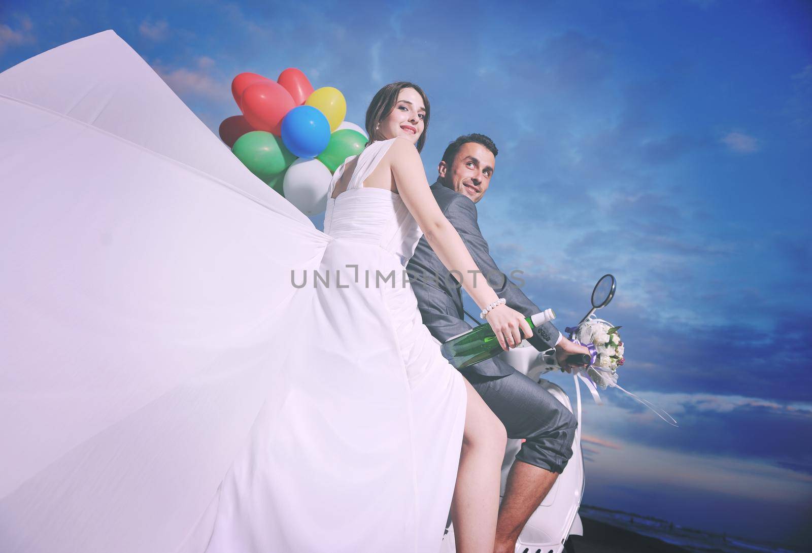 just married couple on the beach ride white scooter by dotshock