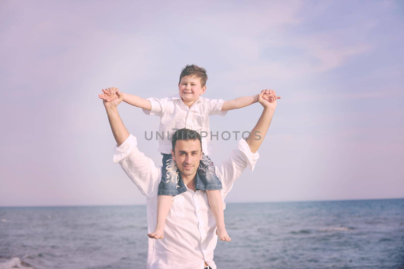 happy young  father and son have fun and enjoy time on beach at sunset and representing healthy family and support concept