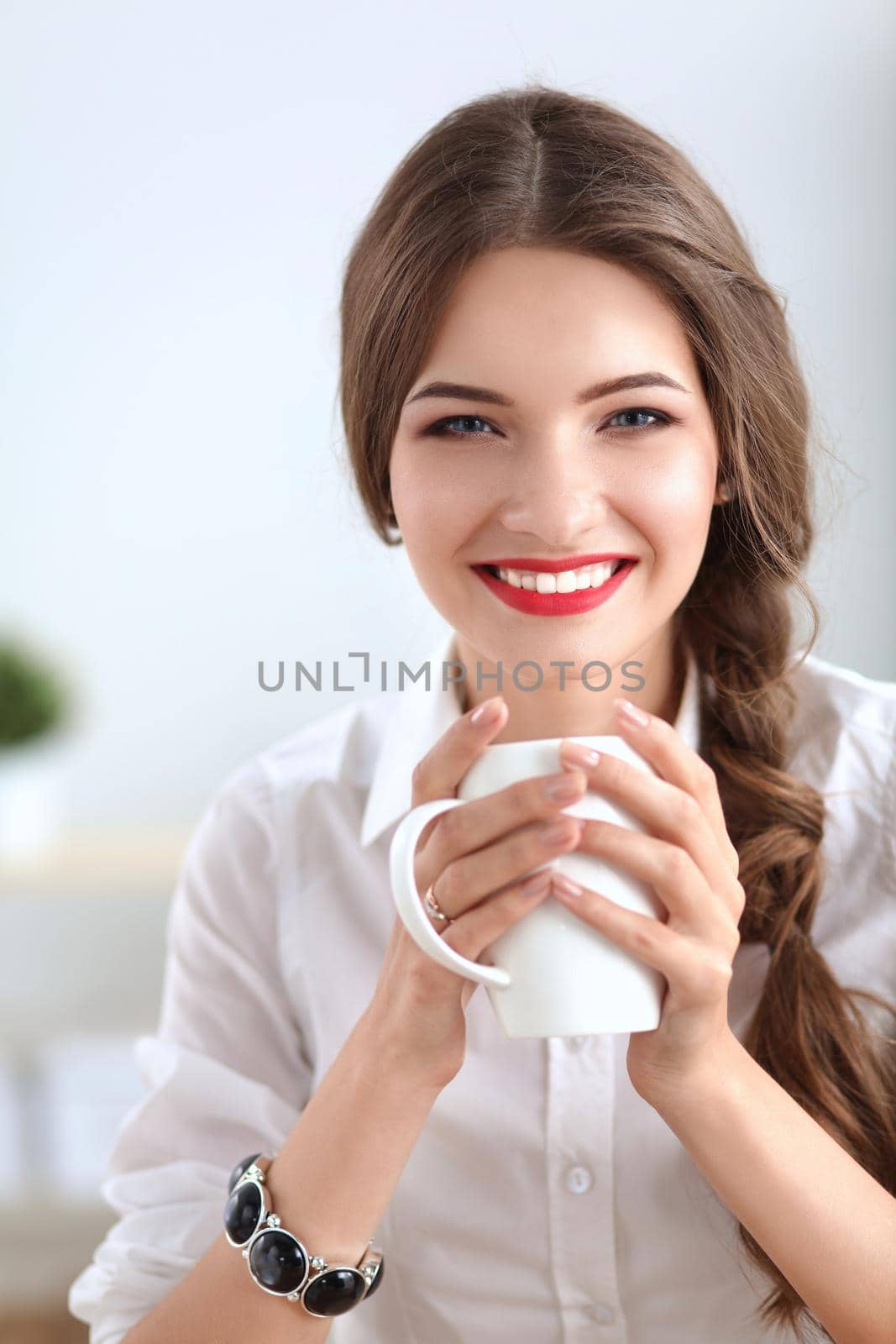 Attractive businesswoman sitting on desk in the office by lenetstan