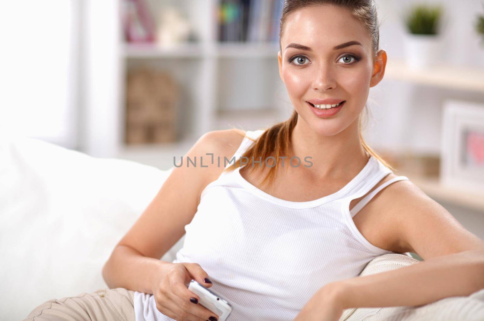 Portrait of beautiful woman sitting on couch at her room using phone