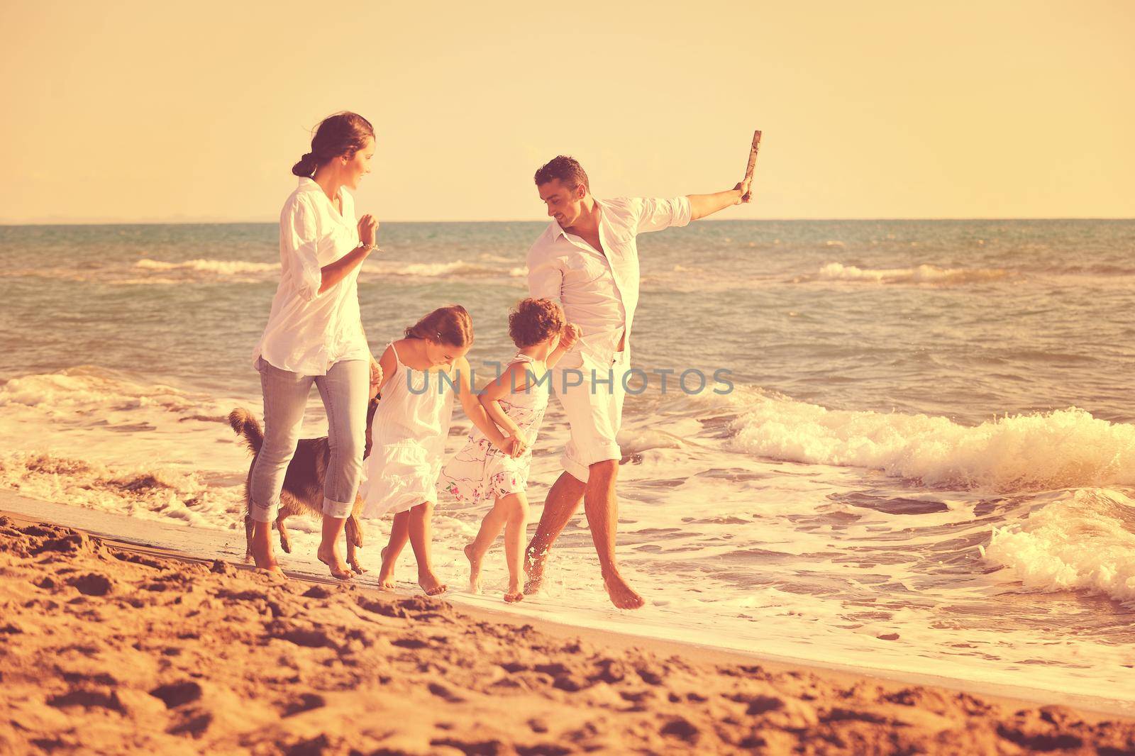 happy family playing with dog on beach by dotshock