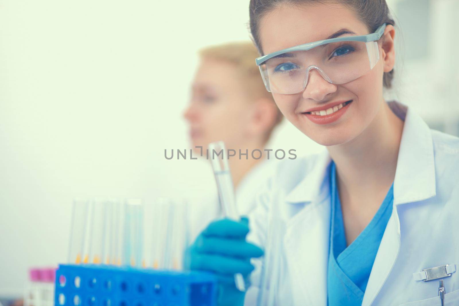 Woman researcher is surrounded by medical vials and flasks, isolated on white background.