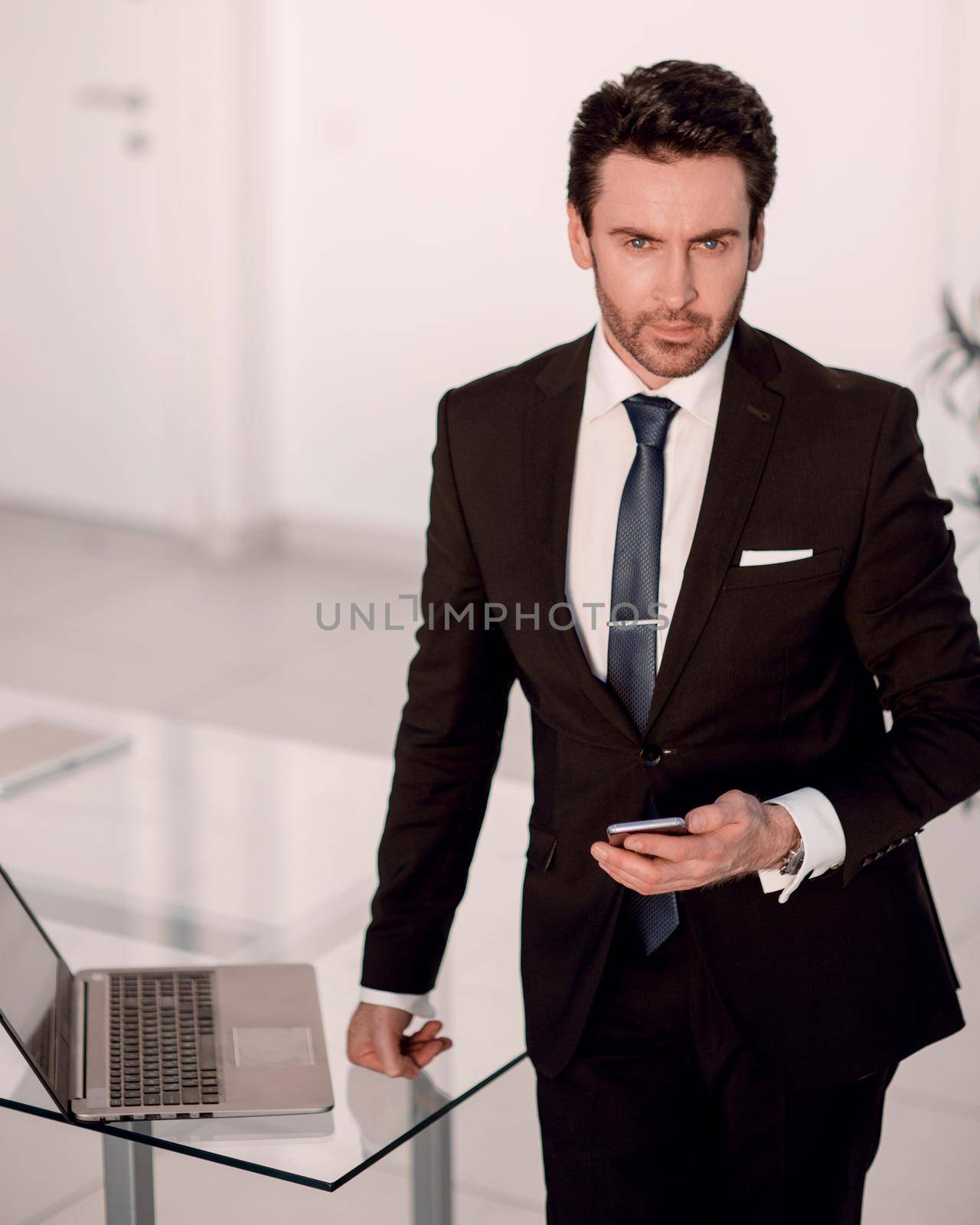 confident businessman standing in the office by asdf
