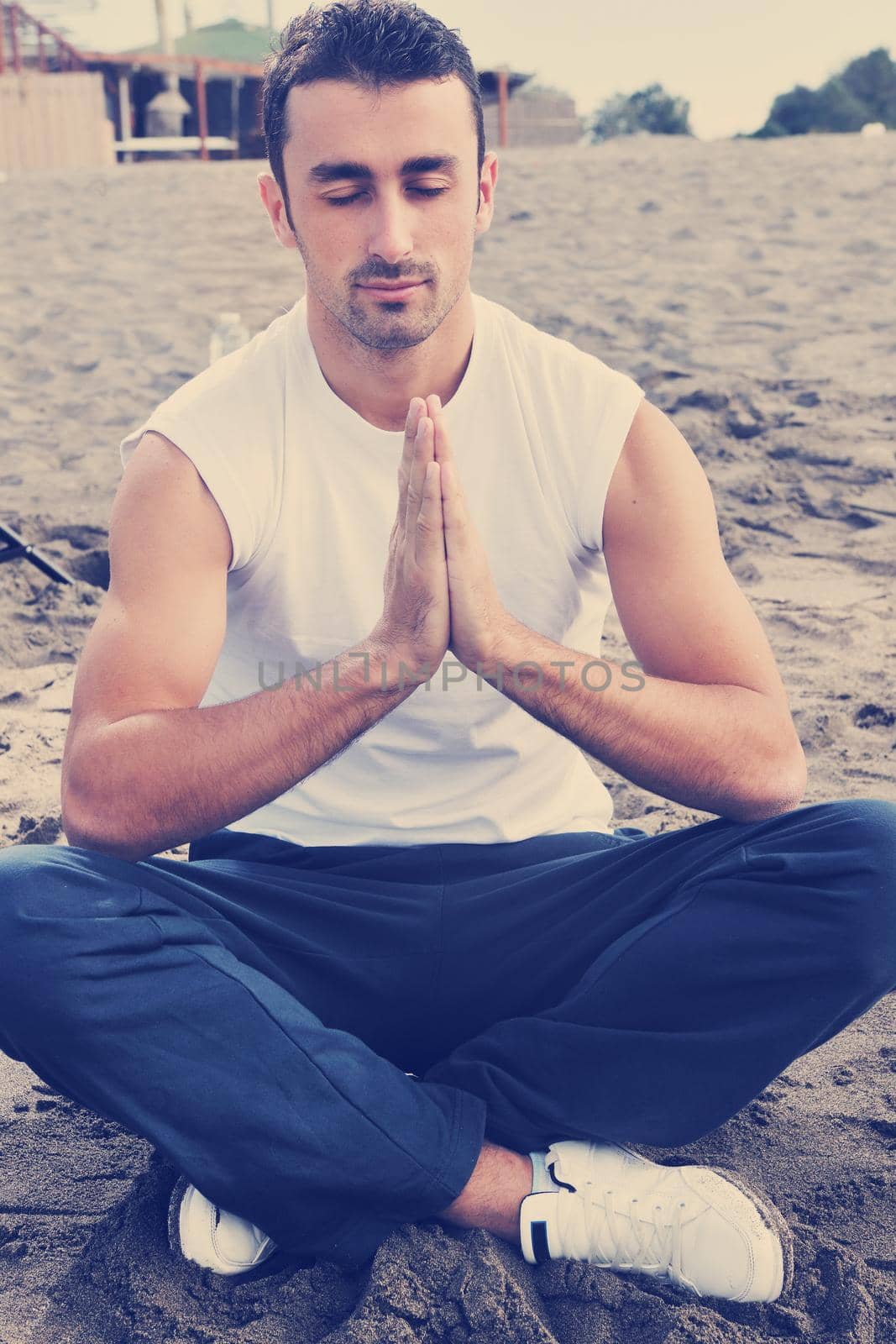 young man meditating yoga in lotus positin on the beach at early morning