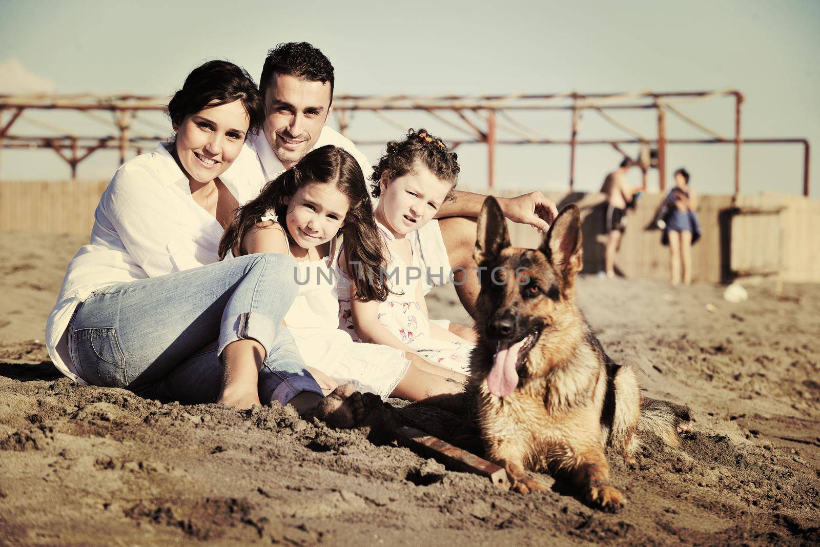 happy young family in white clothing have fun and play with beautiful dog at vacations on beautiful beach 