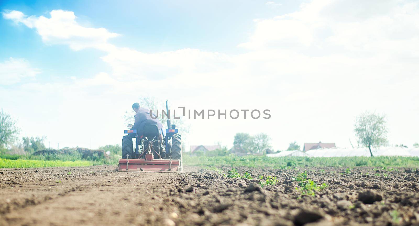 Farmer on a tractor with milling machine loosens, grinds and mixes soil. Farming and agriculture. Loosening the surface, cultivating the land for further planting. Cultivation technology equipment by iLixe48