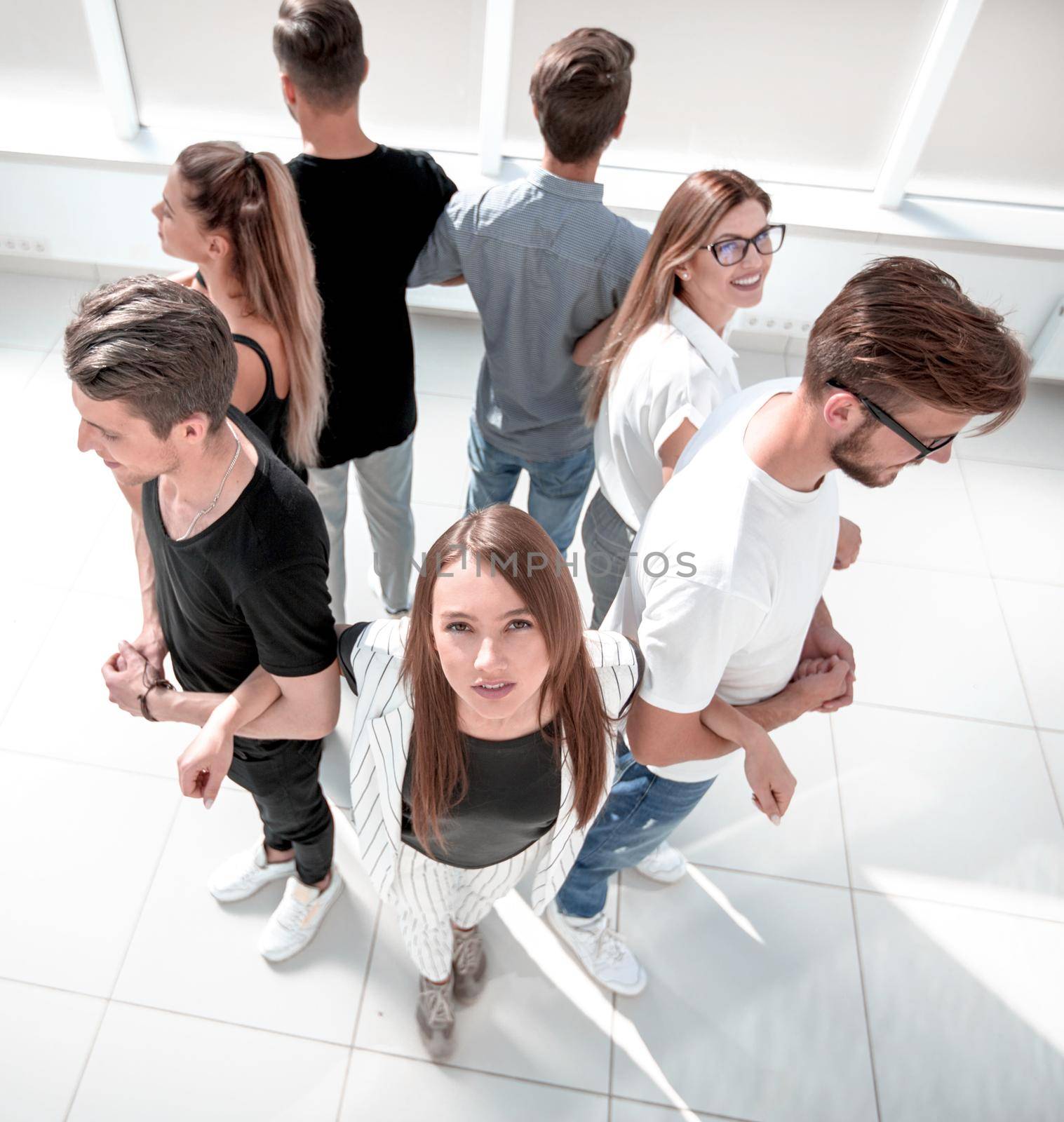 Top view of a positive diverse group of happy people in smart everyday clothes tied together and standing in a circle