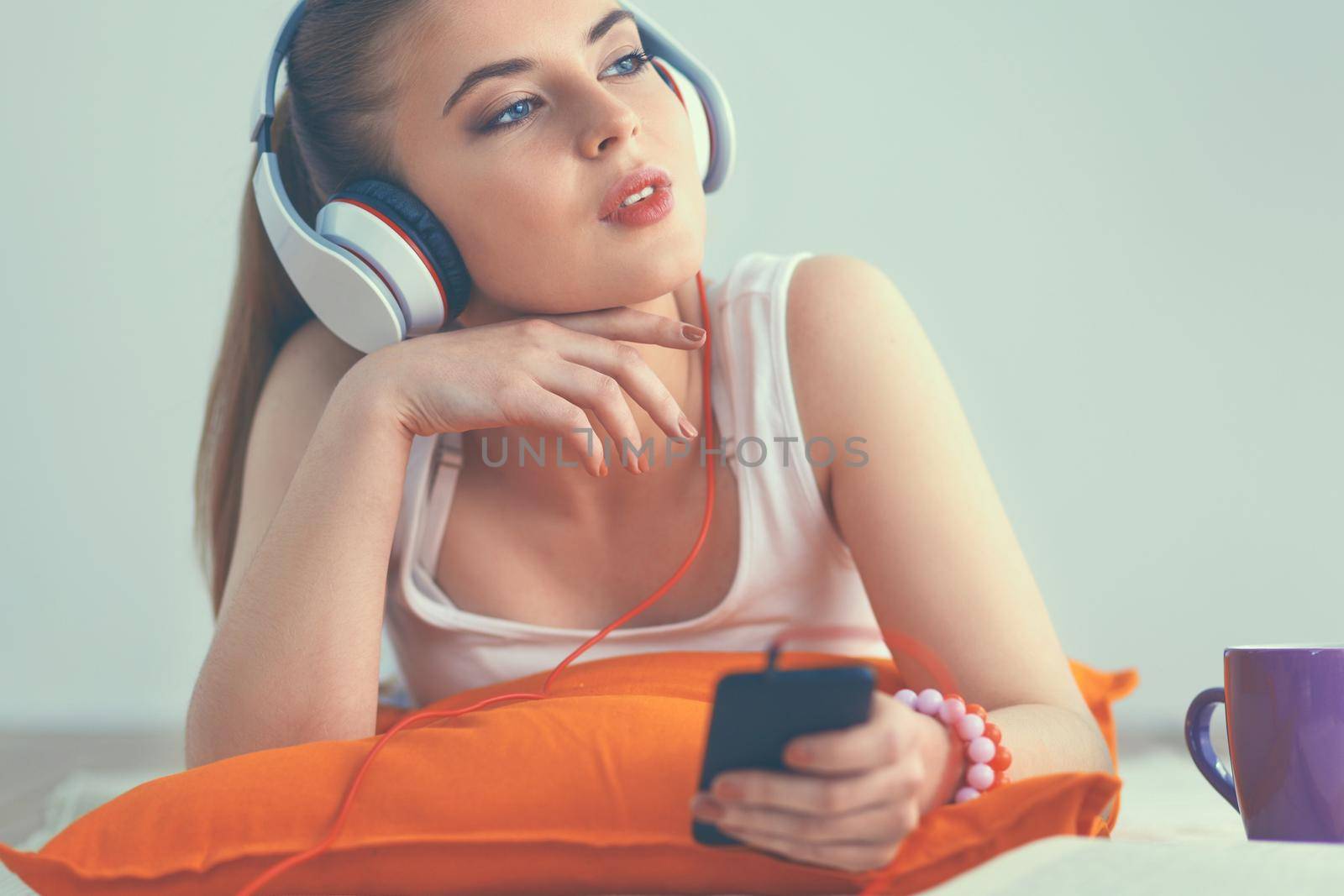 Young woman lying on floor and listen to music.