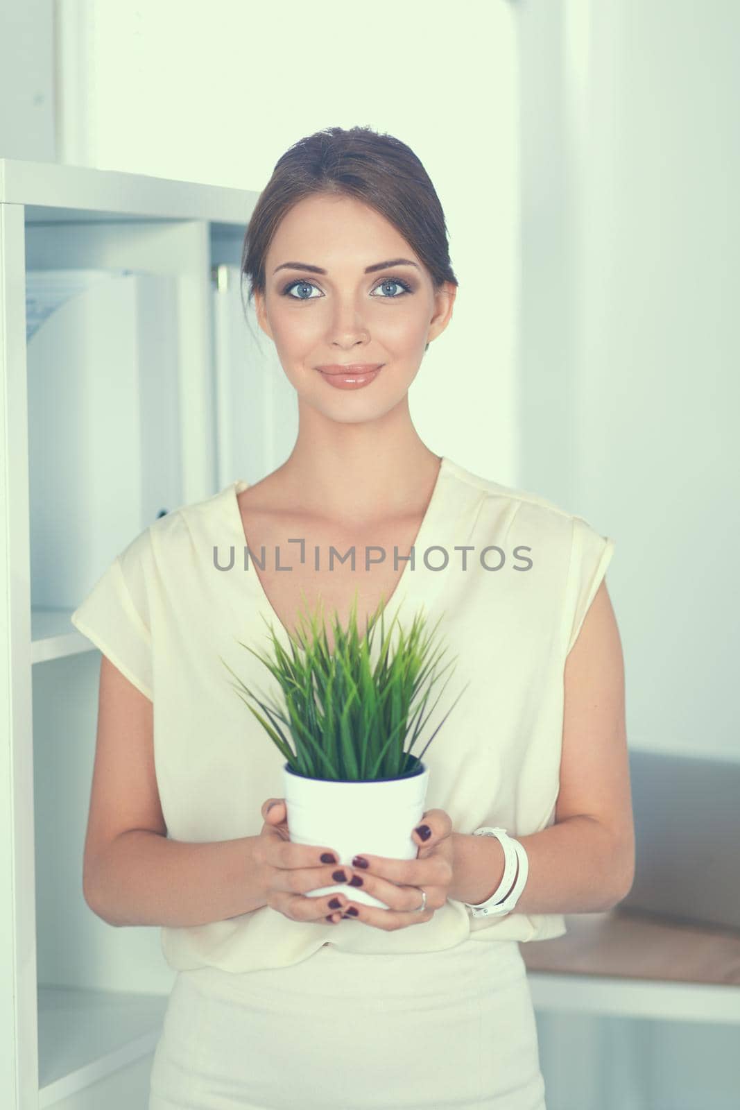 Beautiful woman holding pot with a plant .