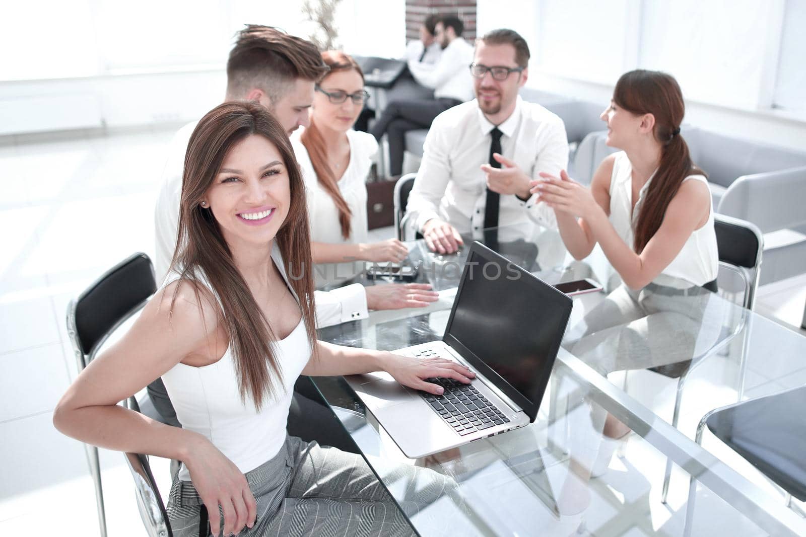 young business woman and her colleagues sitting at the office table by asdf