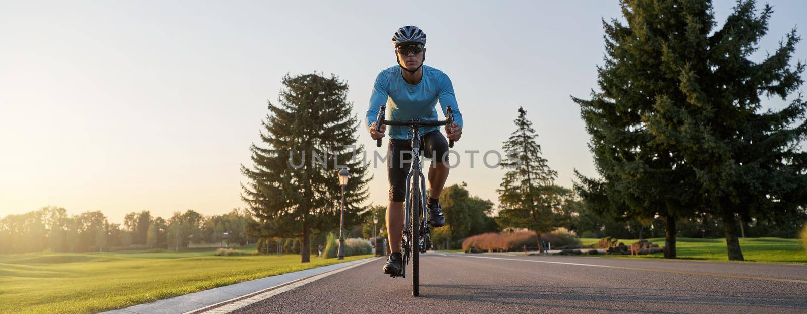 Website header of Cropped shot of a man riding mountain bike in park during sunset, cycling outdoors on a summer day by friendsstock