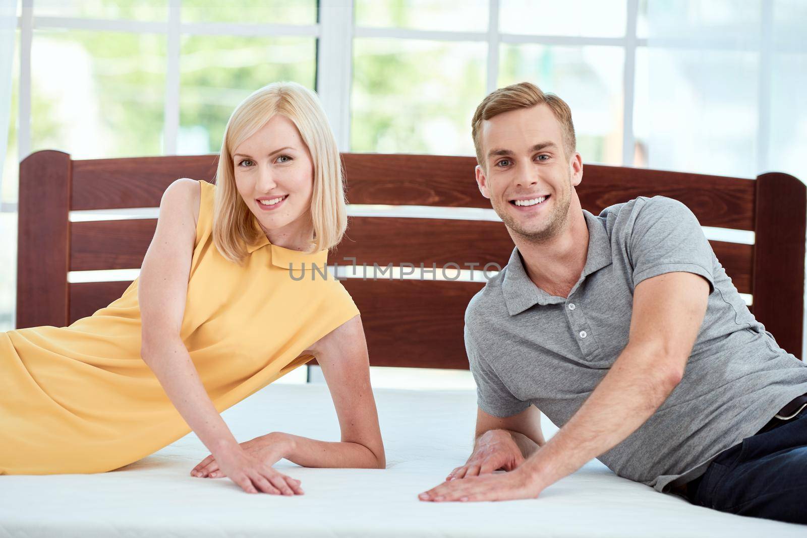 Portrait of beautiful and happy young couple testing a new ergonomic mattress for their bed and smiling at camera. Healthcare. Family concept. Hope. Bedroom