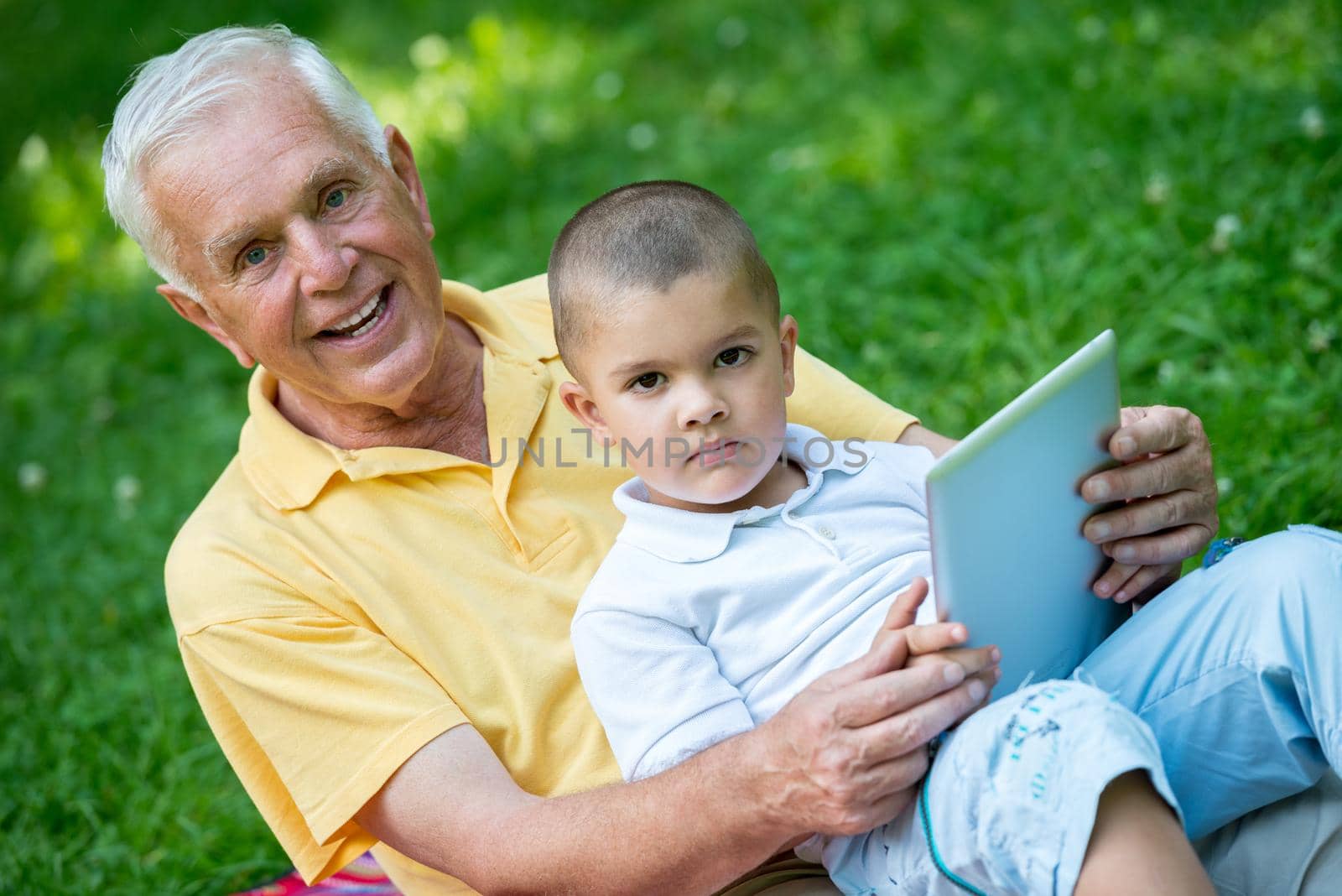 grandfather and child using tablet computer in park