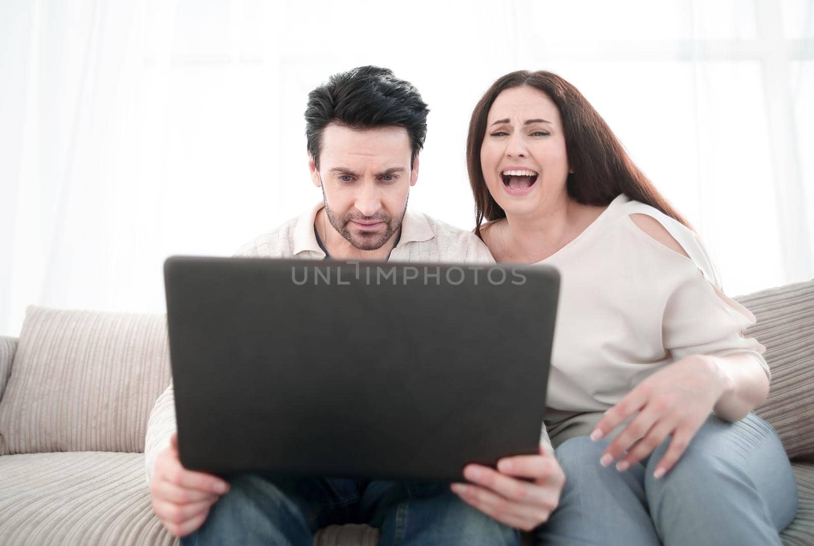 Happy couple sitting on sofa and using laptop at home.photo with copy space