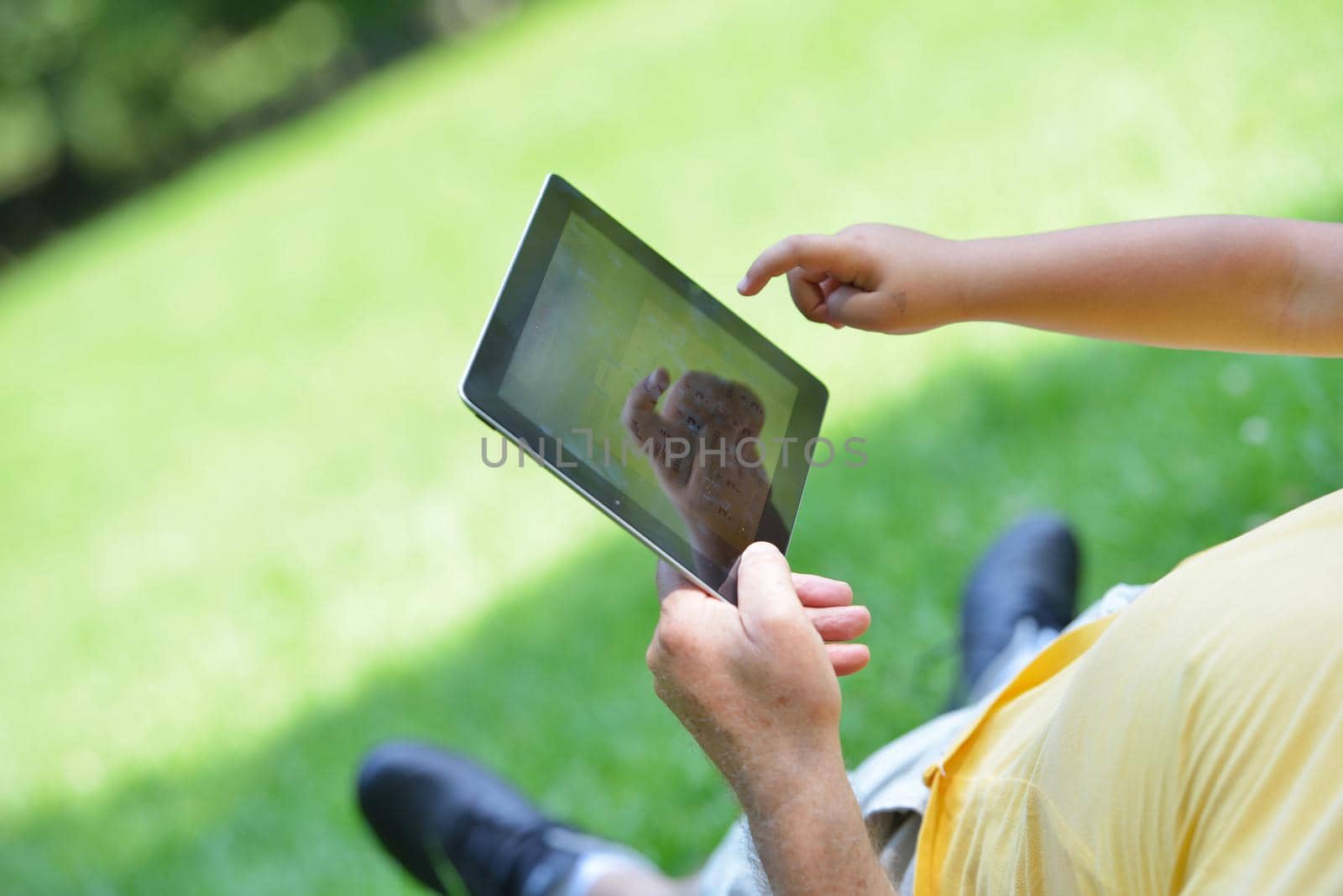 grandfather and child in park using tablet computer