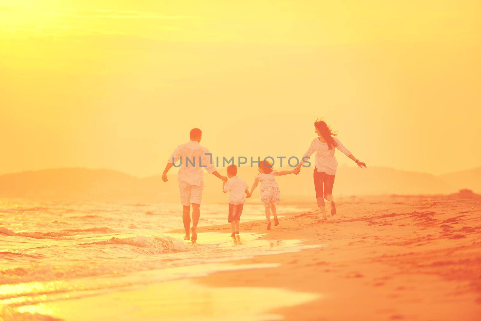 happy young family have fun on beach at sunset by dotshock