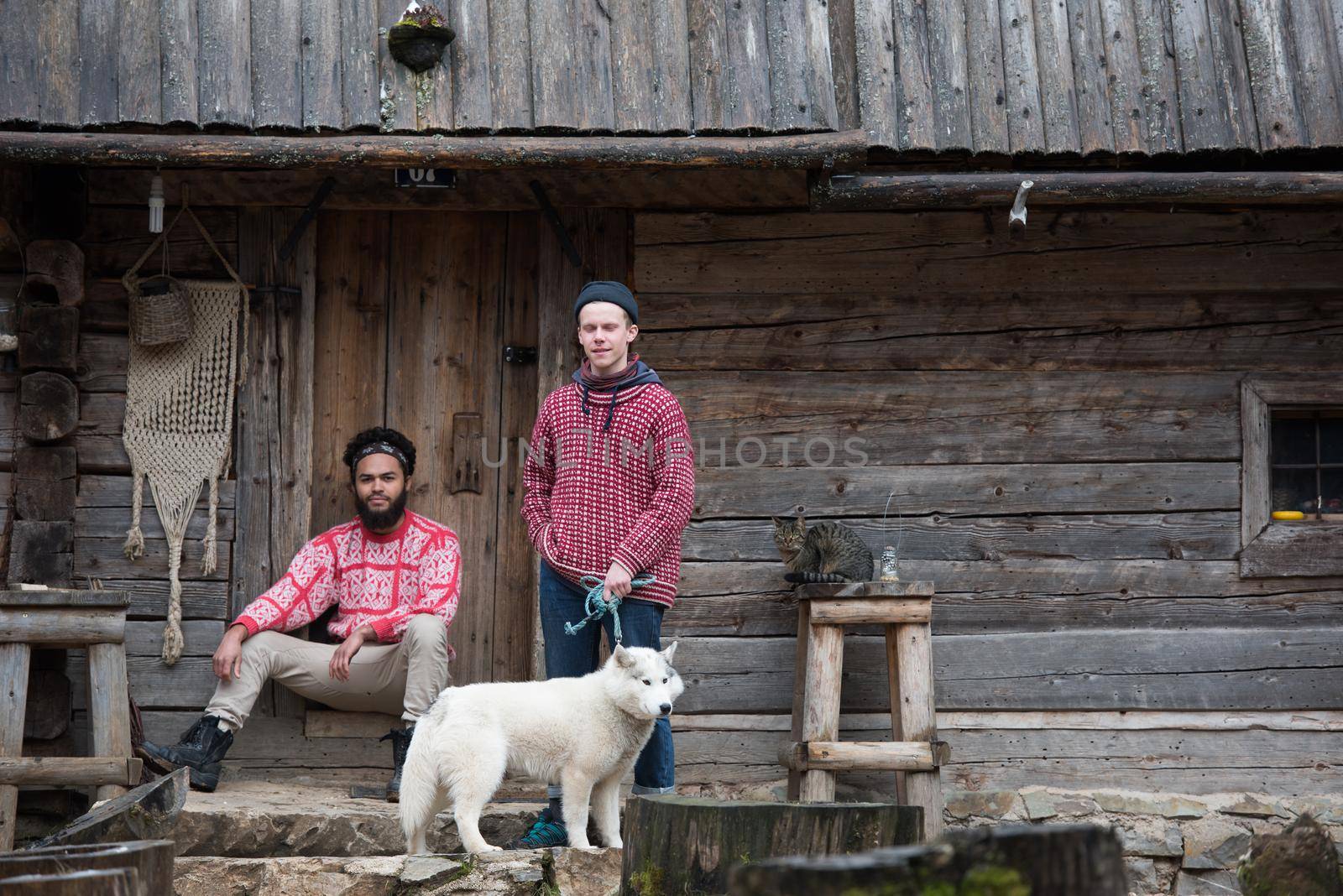 hipsters couple portrait, two young  man with white husky dog  sitting in front of old wooden retro house