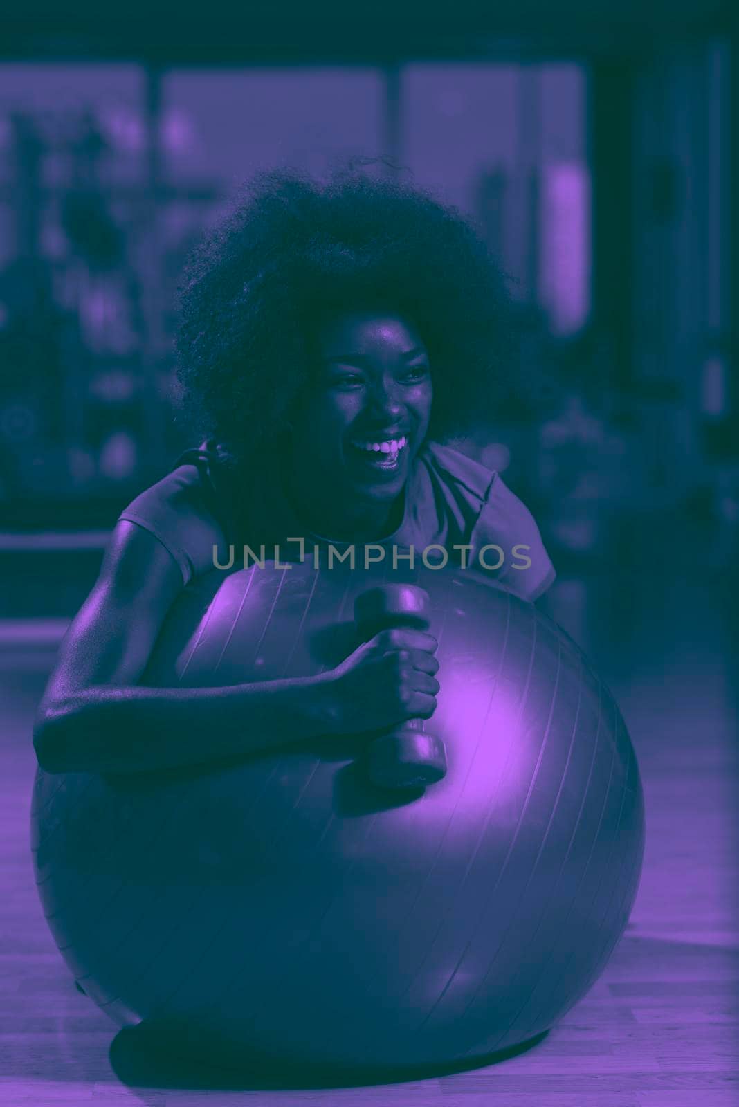 happy african american woman with a curly afro hairstyle in a  gym relaxing after pilates workout duo tone filter