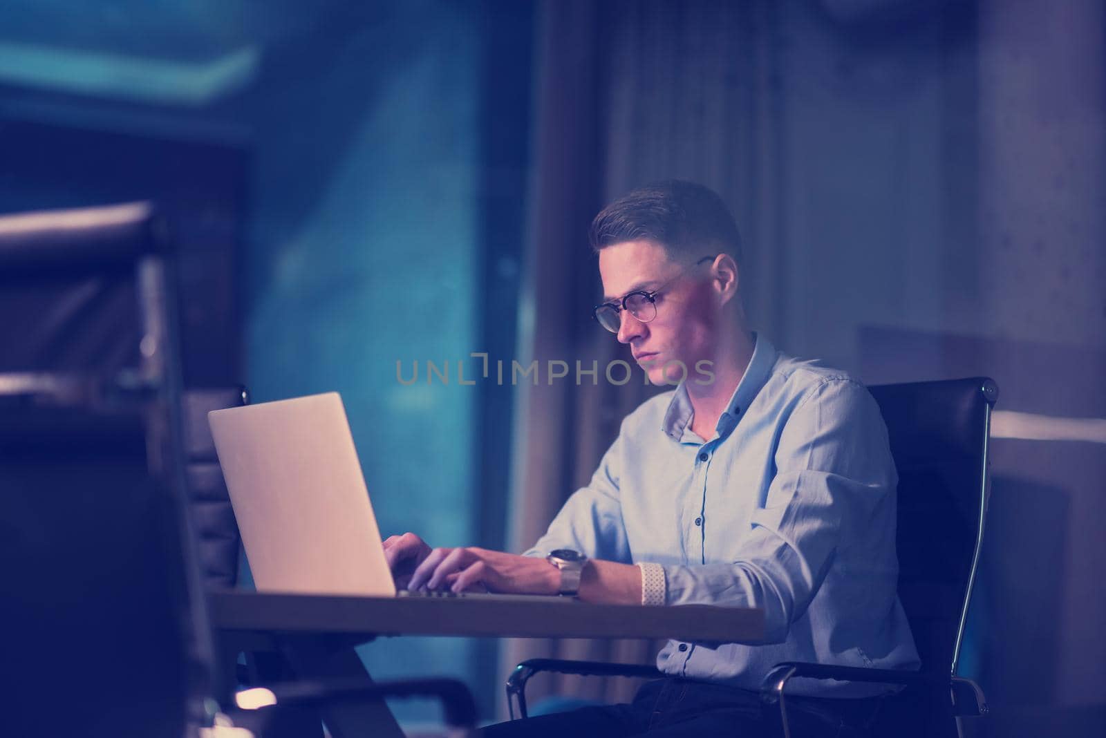 man working on laptop in dark office by dotshock