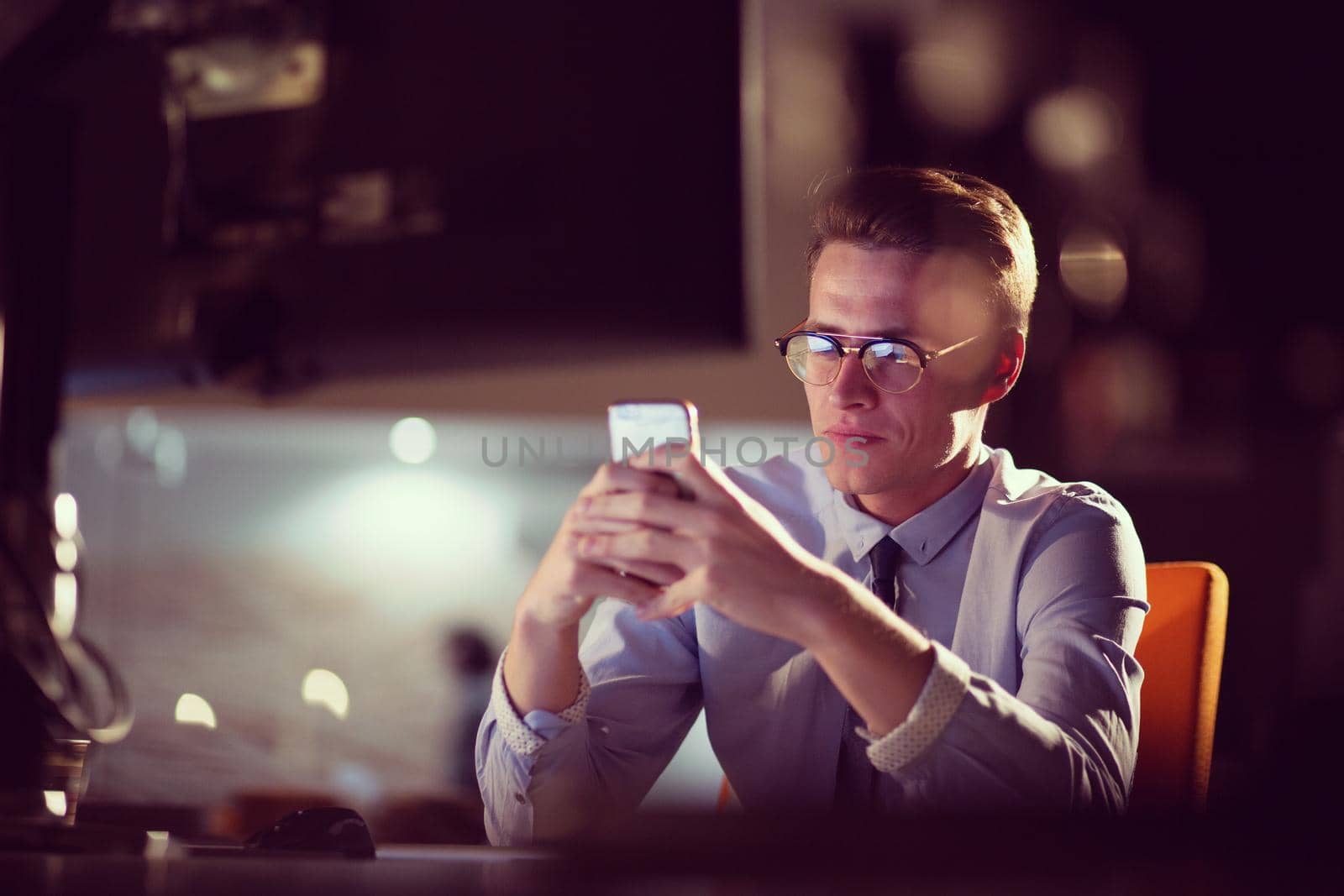 man using mobile phone in dark office by dotshock