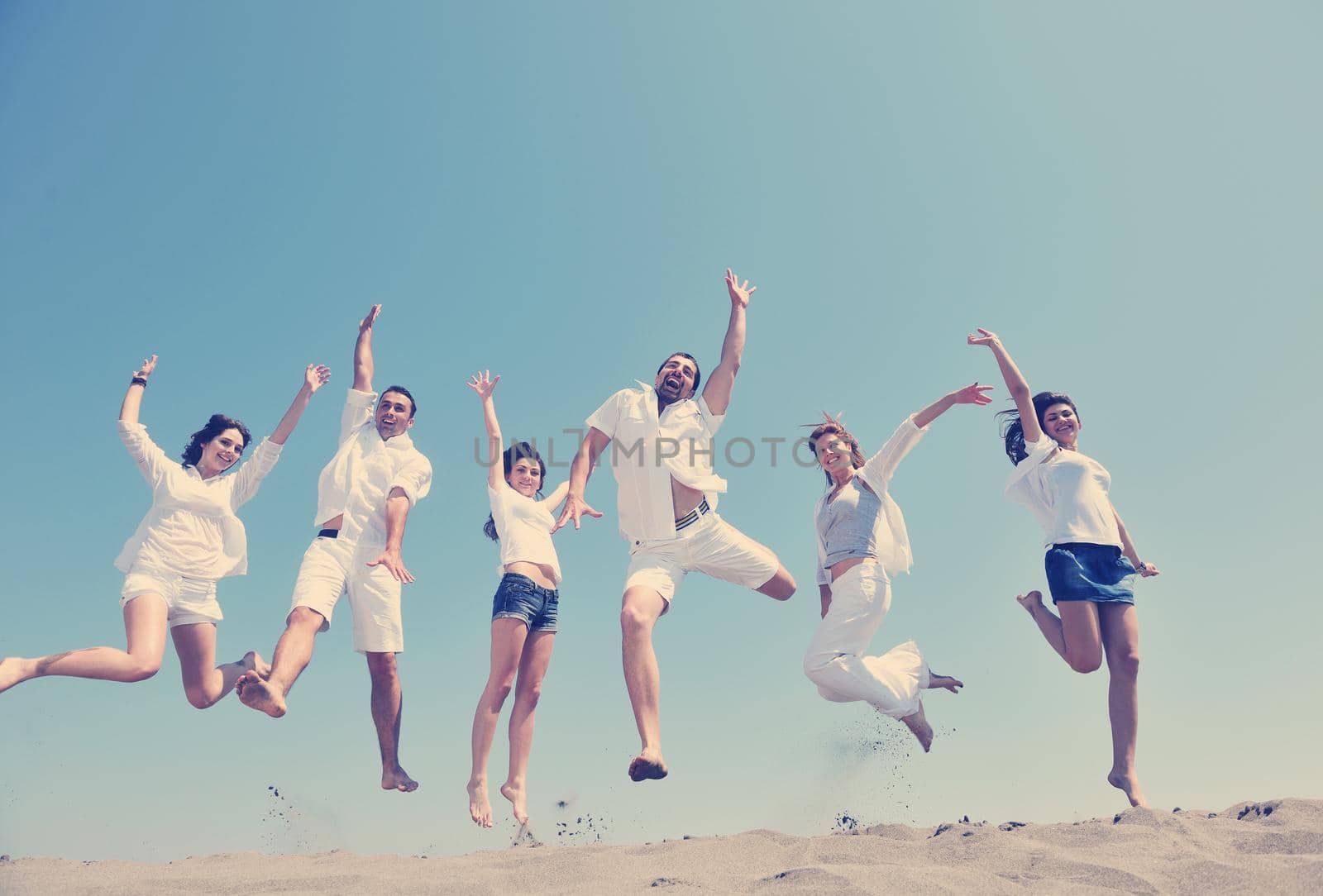 happy people group have fun and running on beach by dotshock