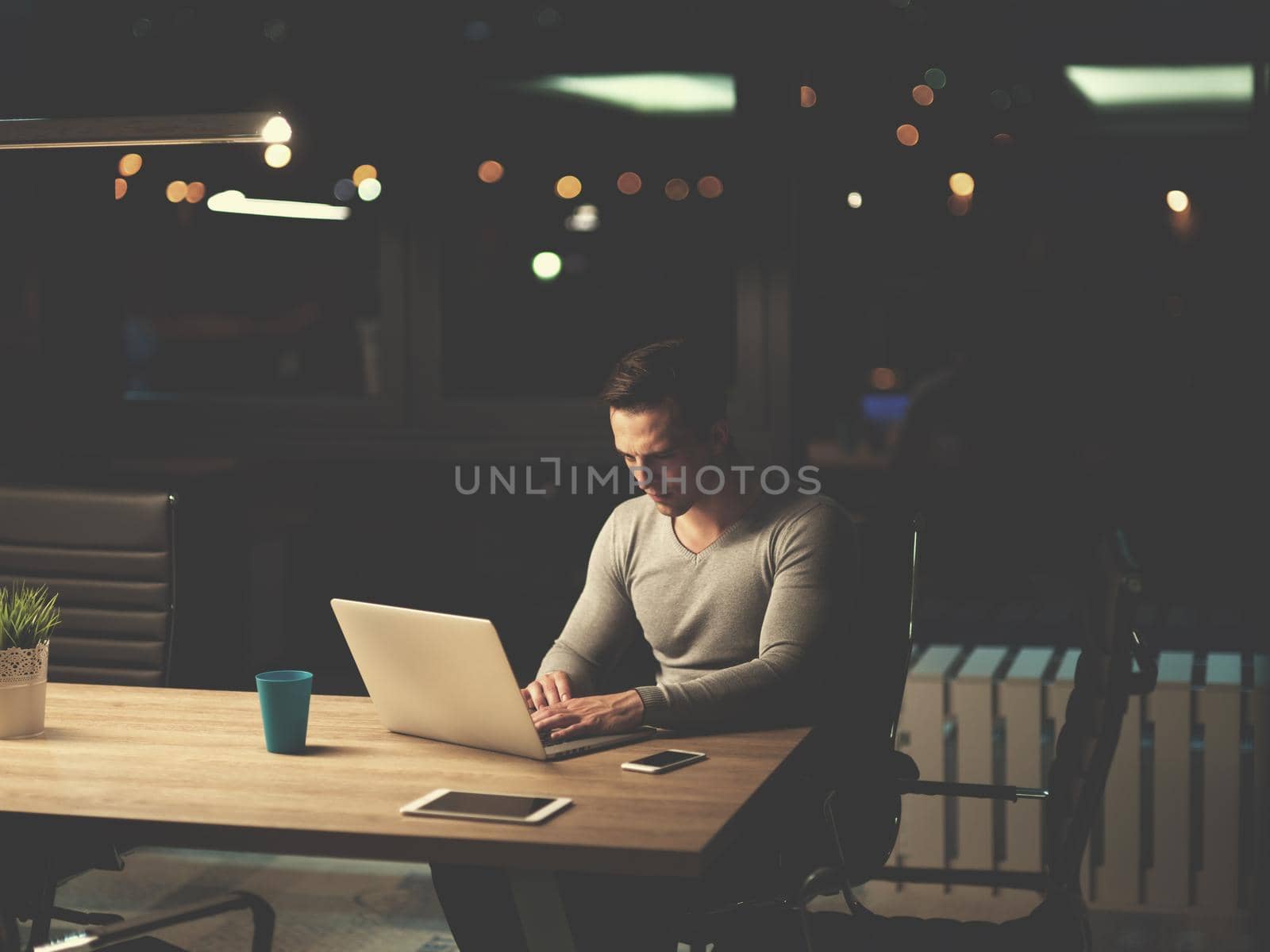 man working on laptop in dark office by dotshock