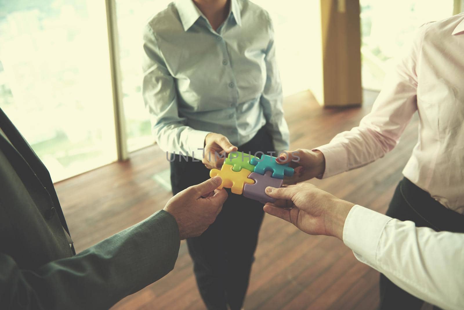 business people group assembling jigsaw puzzle and represent team support and help concept, top view perspective at modern bright office interior