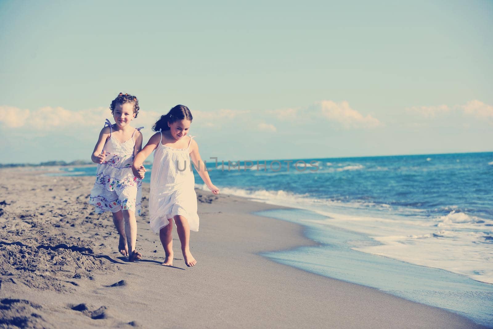 happy two little girls have fun and joy time at beautiful beach while running from joy 